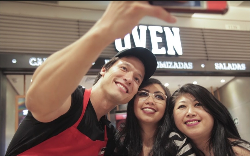 Colaborador da Oven Pizza tirando foto com clientes.