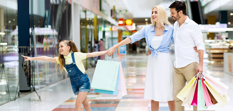 crianca-apontando-para-vitrine-no-shopping-com-os-pais