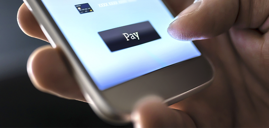 Pessoa segurando um celular com o dedo sobre o botão de pagamento de um site de e-commerce.