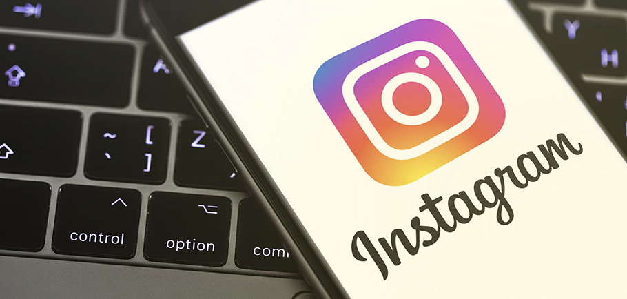 Celular com Instagram aberto em cima de um teclado de notebook.