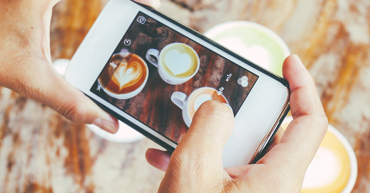 Pessoa tirando foto de cafés decorados para postar no Instagram.
