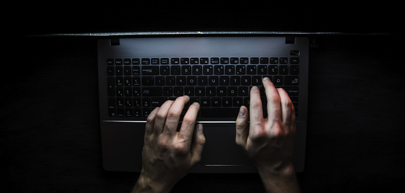 hacker usando o computador em um quarto escuro influenciando pessoas a compartilharem seus dados pessoais 