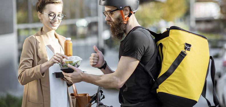 homem usando uma bicicleta para fazer entrega de delivery de comida para uma mulher na era digital