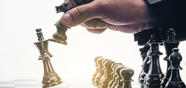 homem derrubando as peças do adversário em um jogo de xadrez, indicando conhecimento da concorrência