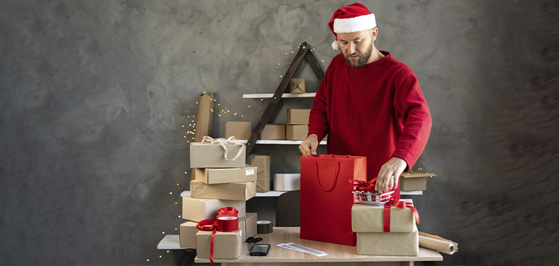 dono de e-commerce usando uma touca de Papai Noel e preparando as mercadorias que serão enviadas